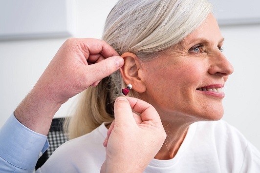 Seniorin erhält ein modernes Hörgerät zur Verbesserung des Hörvermögens im Alltag.